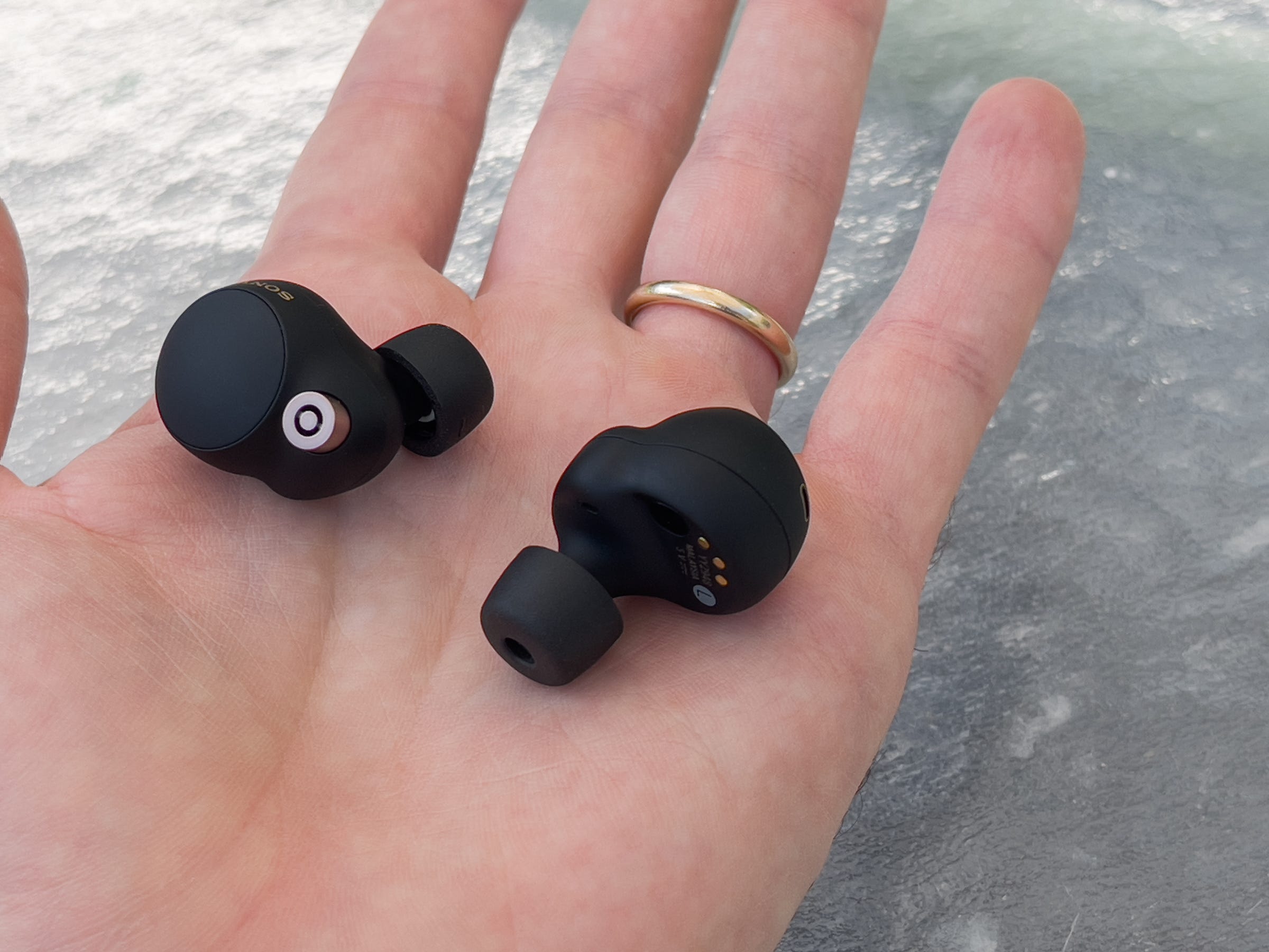 The Sony WF-1000XM4 ear buds in the palm of someones hand