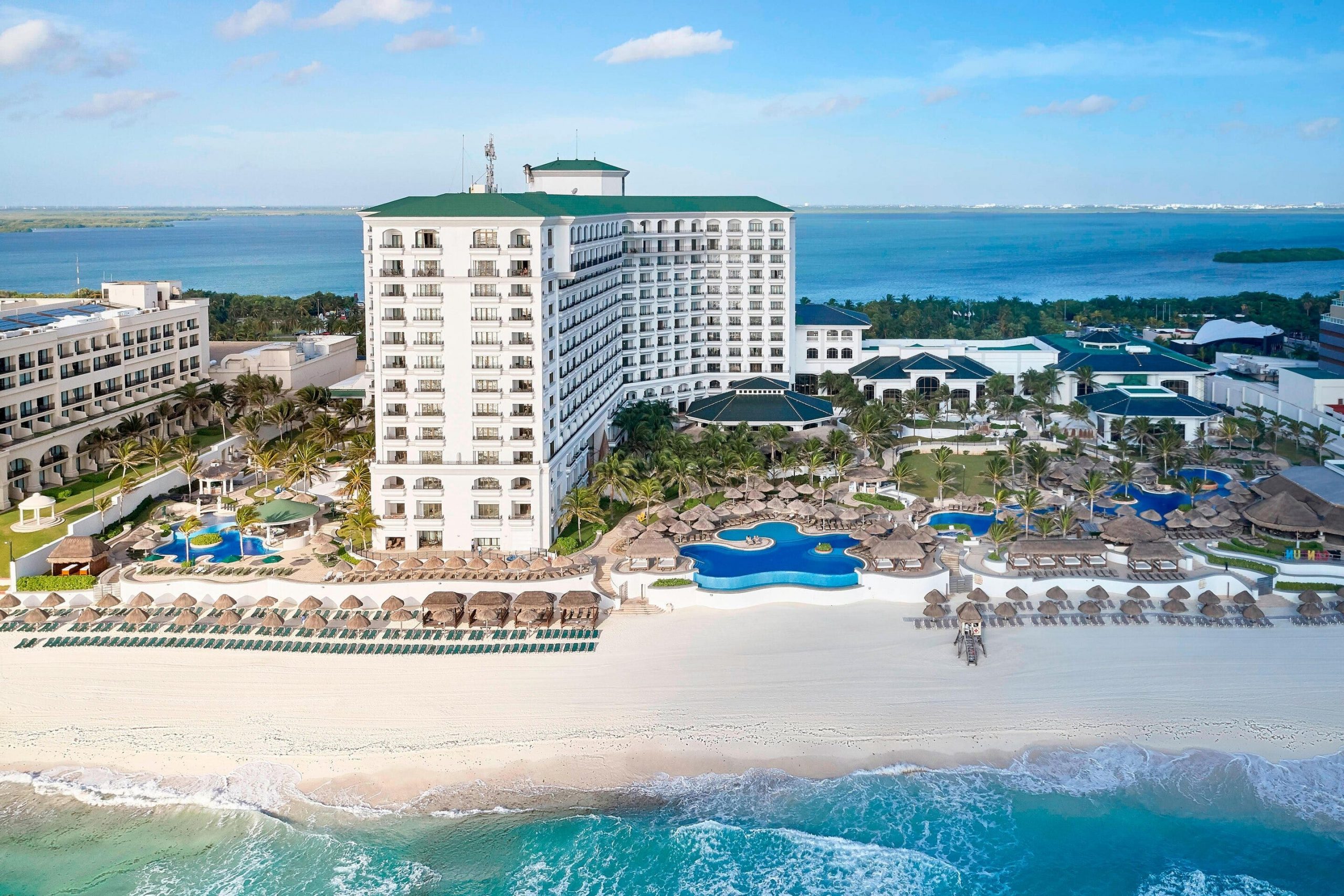 An aerial view of the white sand beach, hotel tower, and pools at the JW Marriott Cancun Resort and Spa.