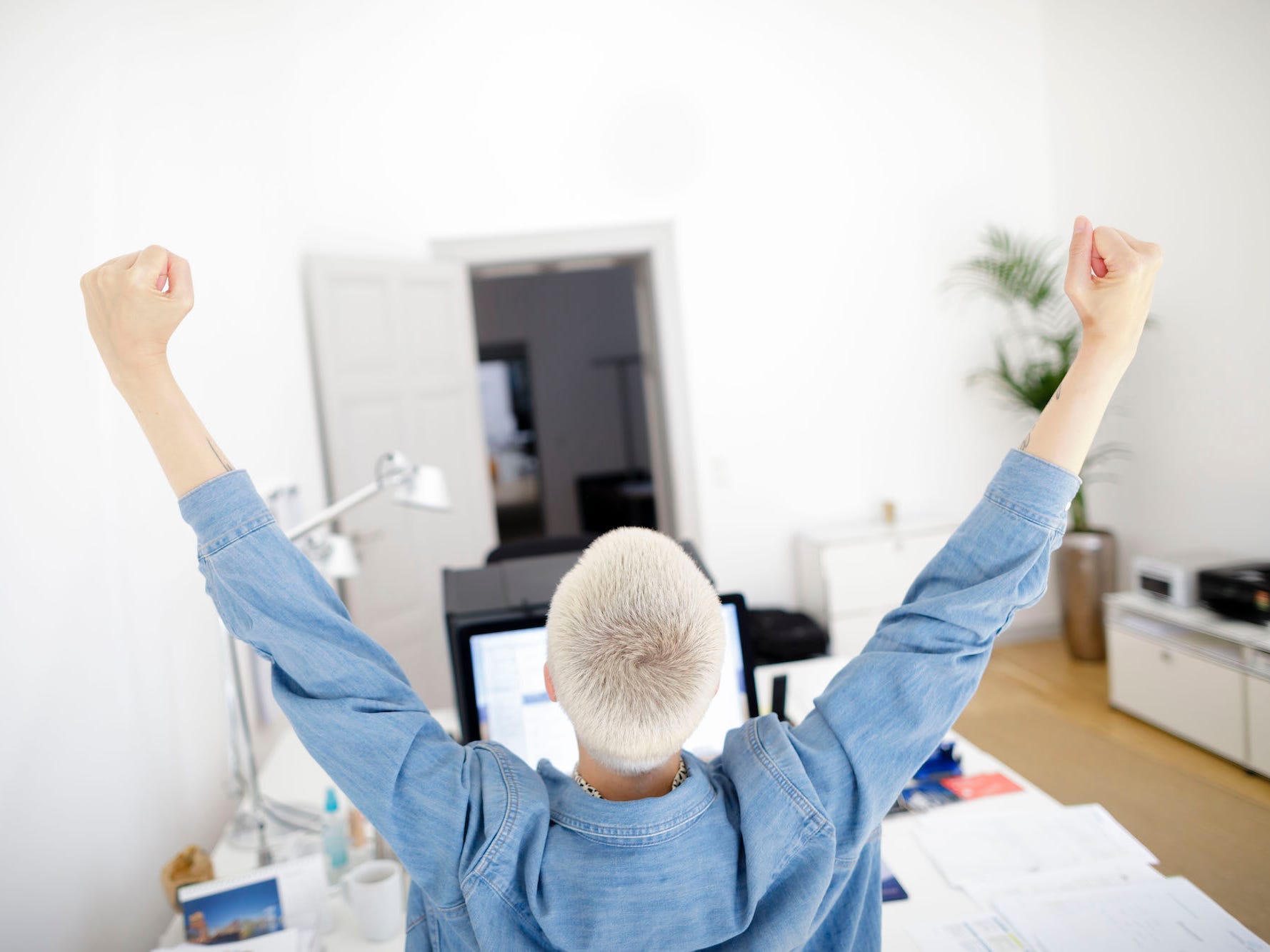 a woman stretches at her desk in her home