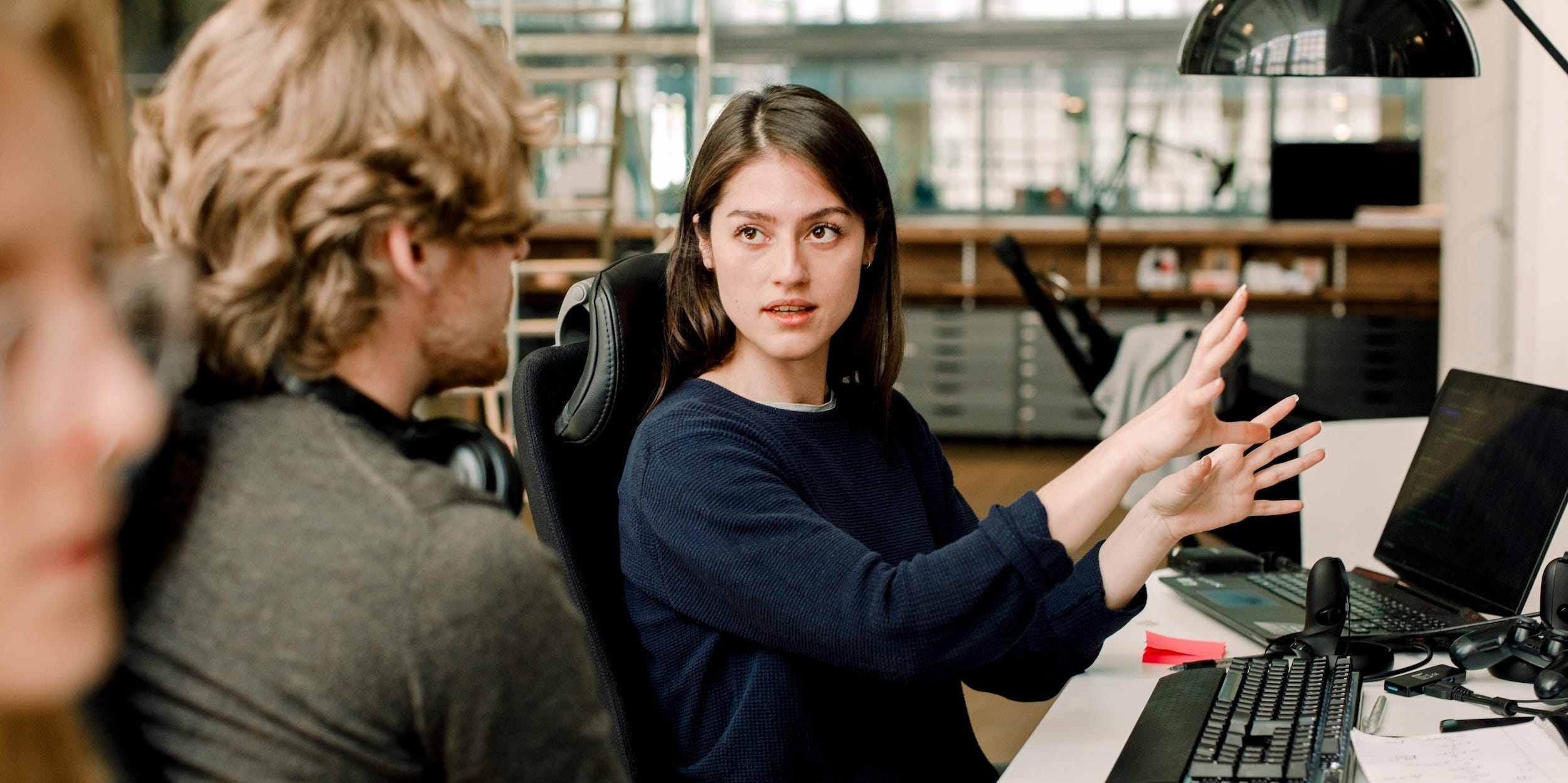 coworker explaining something on computer to other coworkers in office