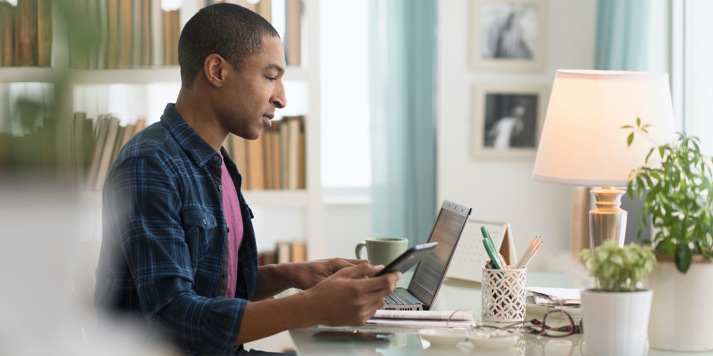 man using phone and laptop at home