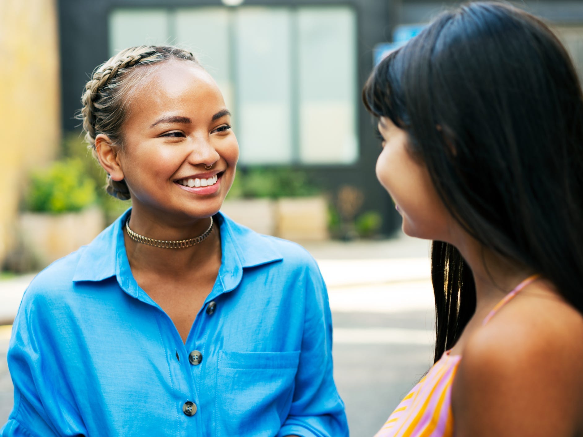 Woman in blue button down smiles while talking to her friend